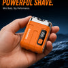 An orange electric shaver is held in a hand against a dark, watery background.