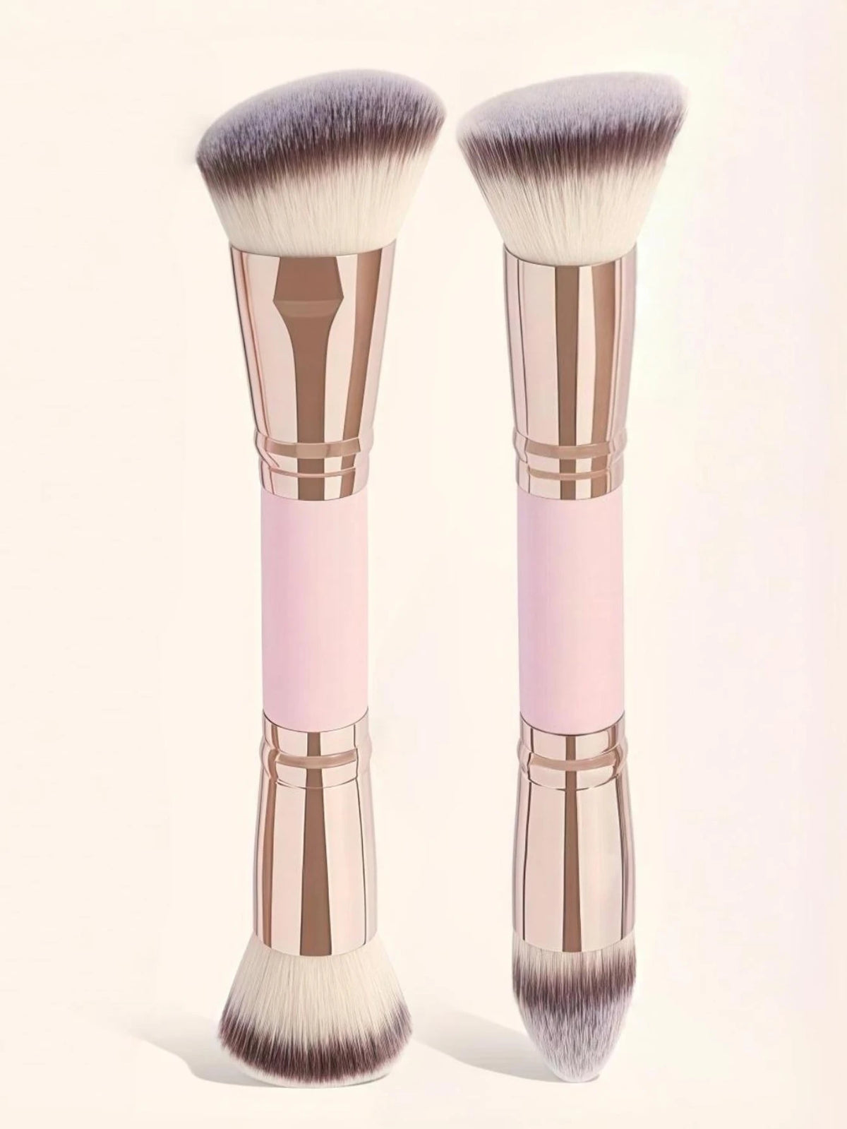 A pair of precision double-ended makeup foundation brushes with pink and rose gold handles and fluffy synthetic bristles.