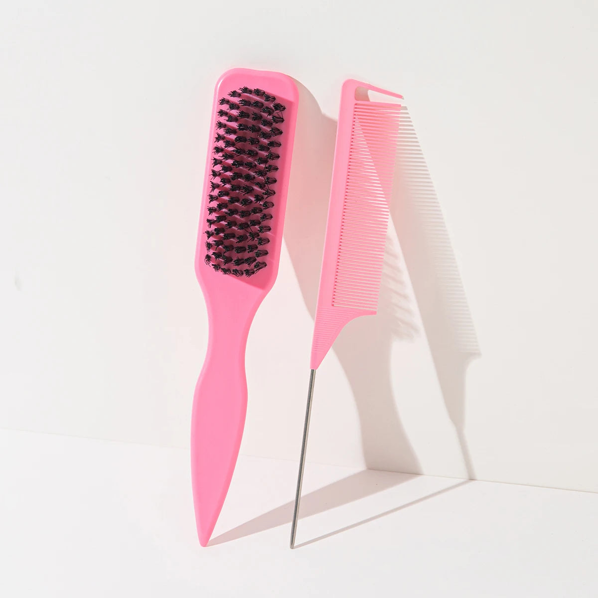 A set of two bright pink hair combs, one shaped like a pointed tail and the other as a straight comb.