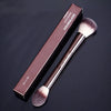 A brown box and matching double-ended makeup powder brush set displayed on a dark background.