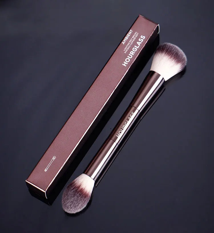 A brown box and matching double-ended makeup powder brush set displayed on a dark background.