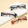 A set of classic black and reddish-brown framed reading glasses displayed on white boxes.