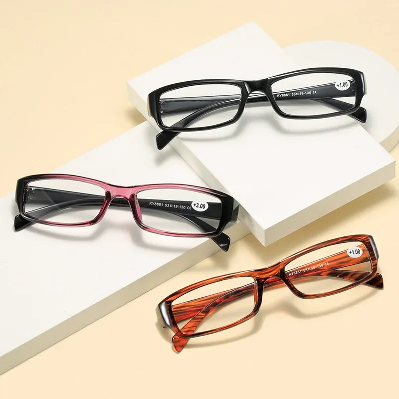 A set of classic black and reddish-brown framed reading glasses displayed on white boxes.
