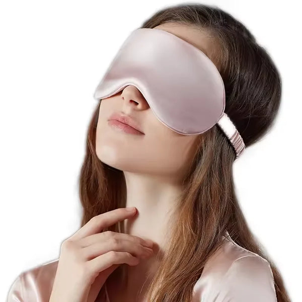 A woman is wearing a pink double-sided silk eye mask while relaxing.
