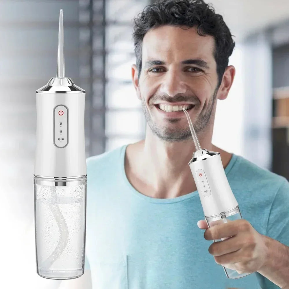 A man holds a portable USB rechargeable dental water flosser device in his hand.