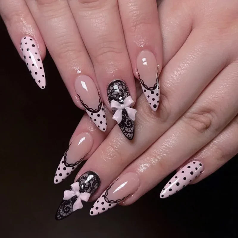 Gros plan de mains présentant des kits de vernis press-on en forme de fleur d'amande à pois noirs et accents blancs
