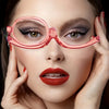 A woman wearing pink magnifying reading glasses with dramatic eye makeup and red lipstick.