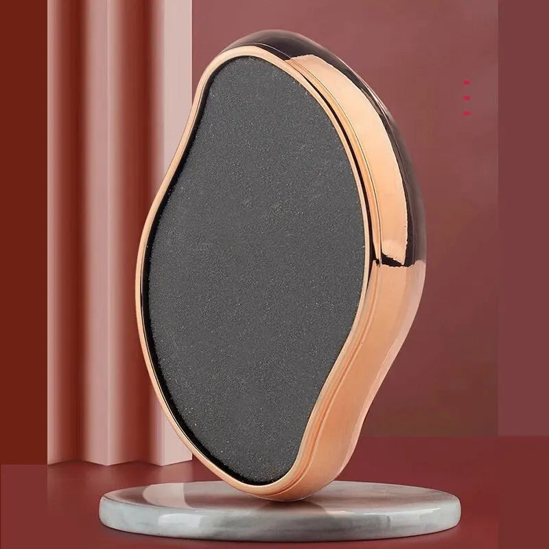A portable glass foot file and callus remover tool with a black surface and rose gold accents resting on a gray base.