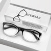 Une paire de lunettes de lecture avec des montures noires posée sur une boîte blanche marquée « EYEWEAR ».