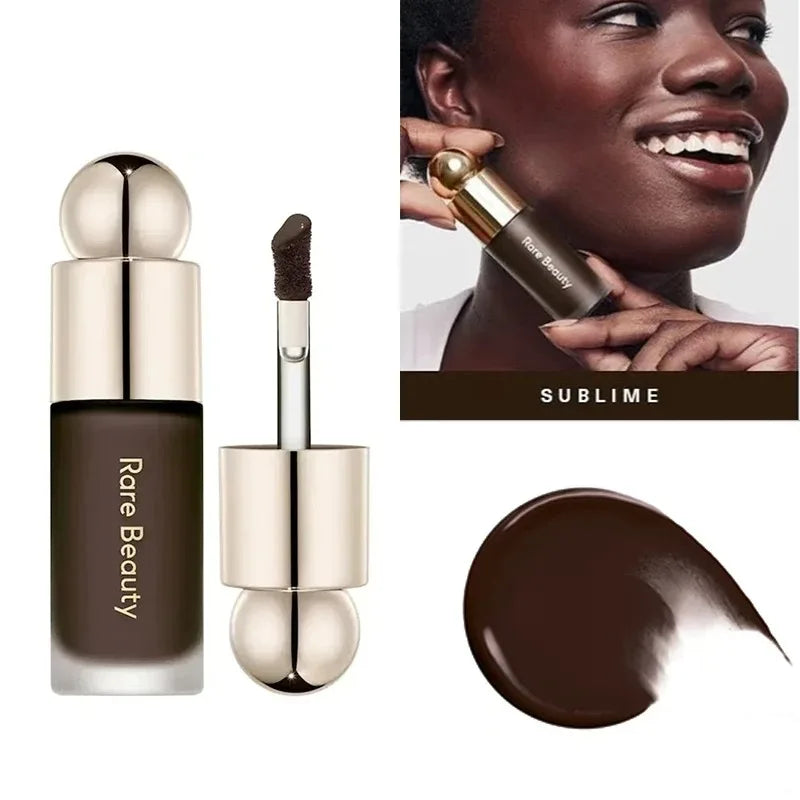 A tube of Rare Beauty liquid bronzer contour foundation stick with a gold applicator and a swatch of the brown product.