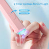 A hand holds a pink handheld UV nail dryer lamp, demonstrating how to press once or twice for curing.