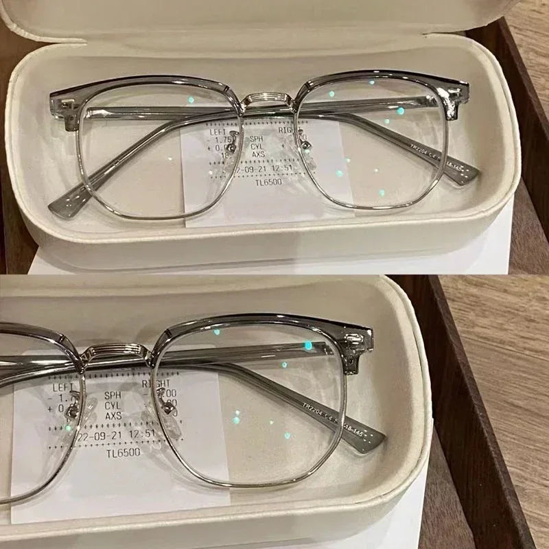 Un par de gafas con marco transparente y detalles plateados, exhibidas en una caja blanca.
