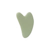 A light green jade gua sha facial stone with a heart-shaped, smooth, polished surface.