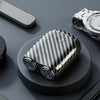 A close-up view of a black and white patterned electric beard trimmer resting on a dark surface next to a silver wristwatch.