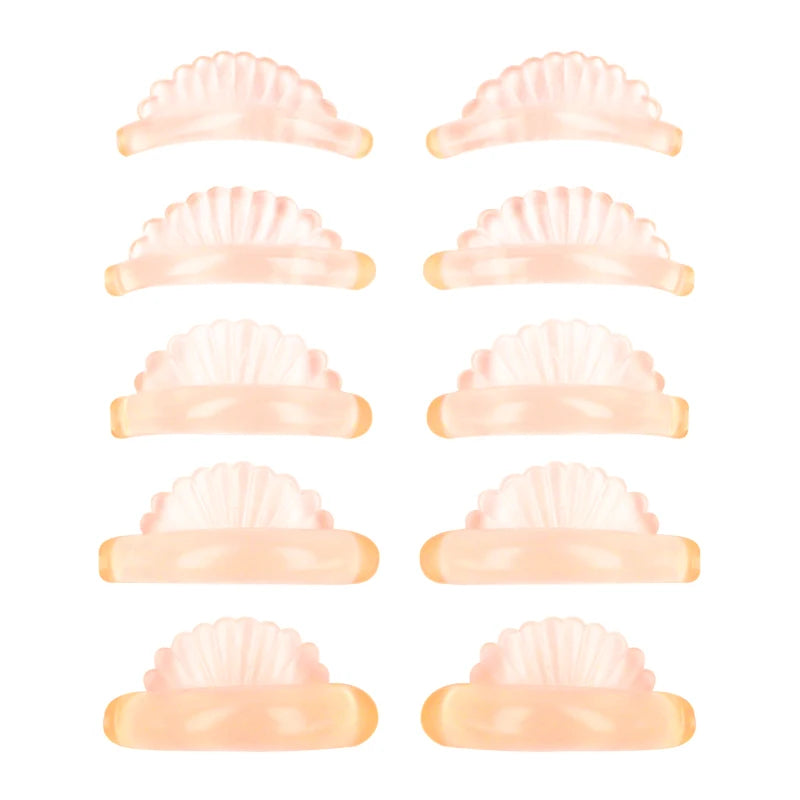 Un jeu de cinq tampons recourbeurs en silicone pour lift de cils, dans diverses nuances de pêche et de rose.