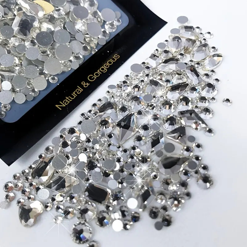 A close-up of a mixed glass rhinestone kit for nail art and DIY crafts showing various clear and silver rhinestones.
