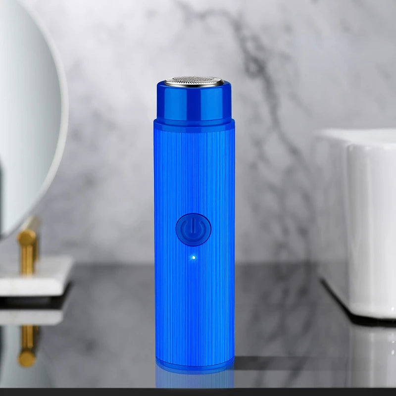 A vertical blue electric shaver with a textured body and a round power button is displayed on a reflective surface.