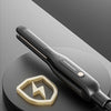A black ceramic hair straightener is shown resting on a dark surface, highlighting its design.
