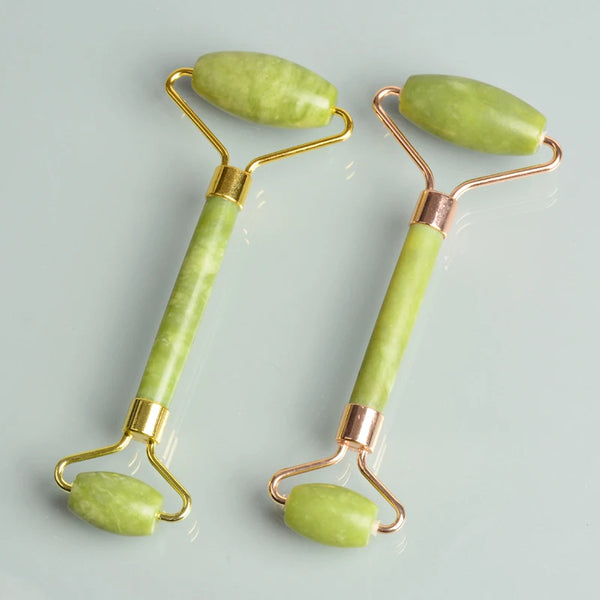 A pair of jade gua sha facial massagers with gold-toned handles and light green stones.