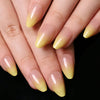 A set of almond press-on nails with a gradient yellow to pink bow design displayed on hands.