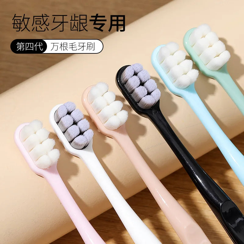 A set of four soft bristled toothbrushes in various pastel colors, including pink, white, and light green, displayed on a woo