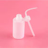 A clear plastic bottle for eyelash extension cleaning with a precision applicator brush on a pink background.