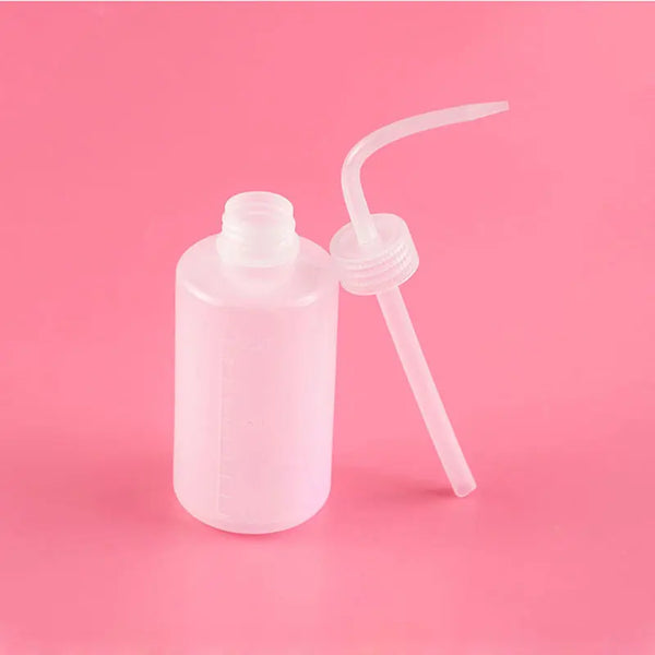 A clear plastic bottle for eyelash extension cleaning with a precision applicator brush on a pink background.
