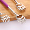 A silver stainless steel telescopic back scratcher with a purple handle resting on a wooden surface.