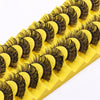 A strip of yellow lash extensions featuring natural wispy black lashes.