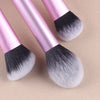 A set of professional makeup brushes with pink handles and black and white synthetic bristles.
