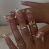 Close-up of a hand displaying long almond shaped press-on false nails with a sheer pink and gold polka dot design