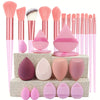A collection of pink and nude makeup brushes and sponges arranged on a textured surface.