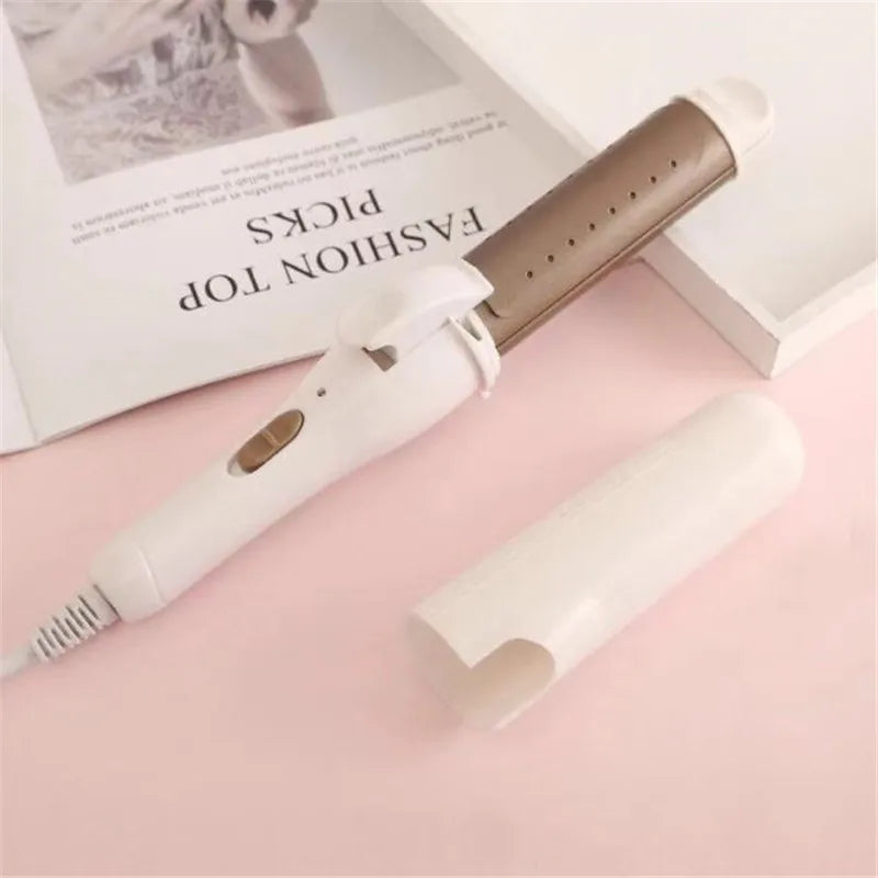A professional ceramic hair curling iron in white and gold is shown next to a magazine.