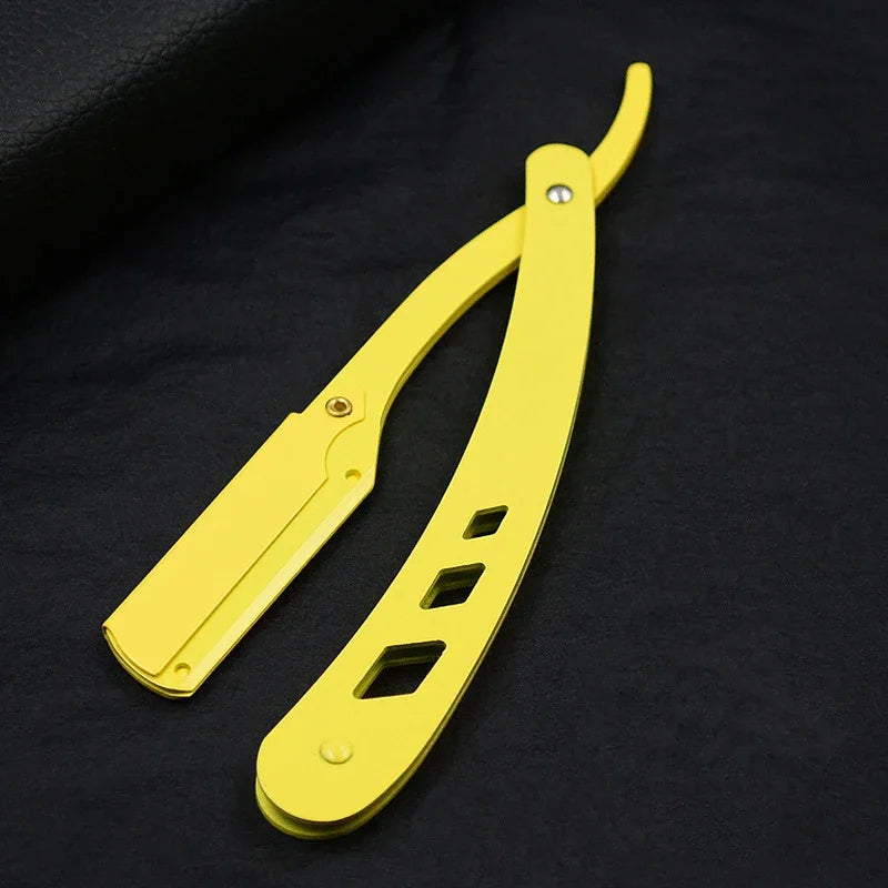 Un rasoir de sûreté antique jaune à pliage avec manche et lame sur fond sombre.