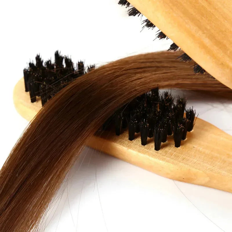 A close-up of a professional double-sided wooden hair comb with dark brown hair being combed.