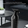 A black professional electric hair trimmer and clipper is shown on a dark table surface.