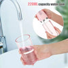 A hand is using a pink 220ml capacity water tank oral irrigator to flush water into a glass.