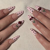Gros plan sur plusieurs ongles décorés de pois roses et noirs et de petites fleurs rouges.