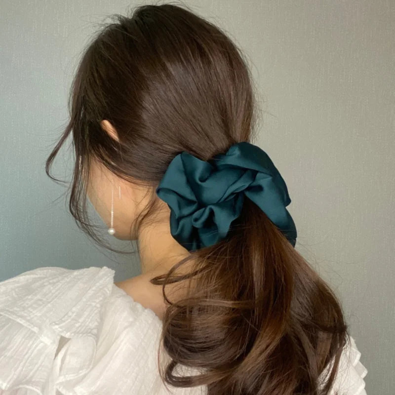 Cheveux brun foncé d'une femme, attachés en queue de cheval basse avec un élastique en mousseline de satin bleu sarcelle