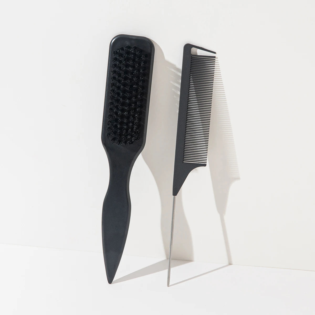 A set of two black hair combs, one paddle-shaped and one thin, pointed comb, shown against a white background.