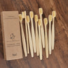 A set of ten natural bamboo toothbrushes standing upright in a cardboard box.