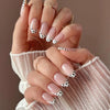 Close-up of hands displaying red pink striped press-on nails with a polka dot design on an almond shape
