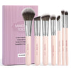 A set of seven pink makeup brushes with silver ferrules displayed in a pink box.