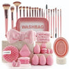 A pink washbag and various makeup brushes, sponges, and tools are displayed on a surface.