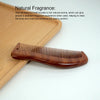 A wooden scalp and hair comb set with serrated teeth resting on a light wooden surface.