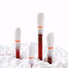 Three disposable medical iodine cotton swabs standing upright on a bed of white cotton balls.