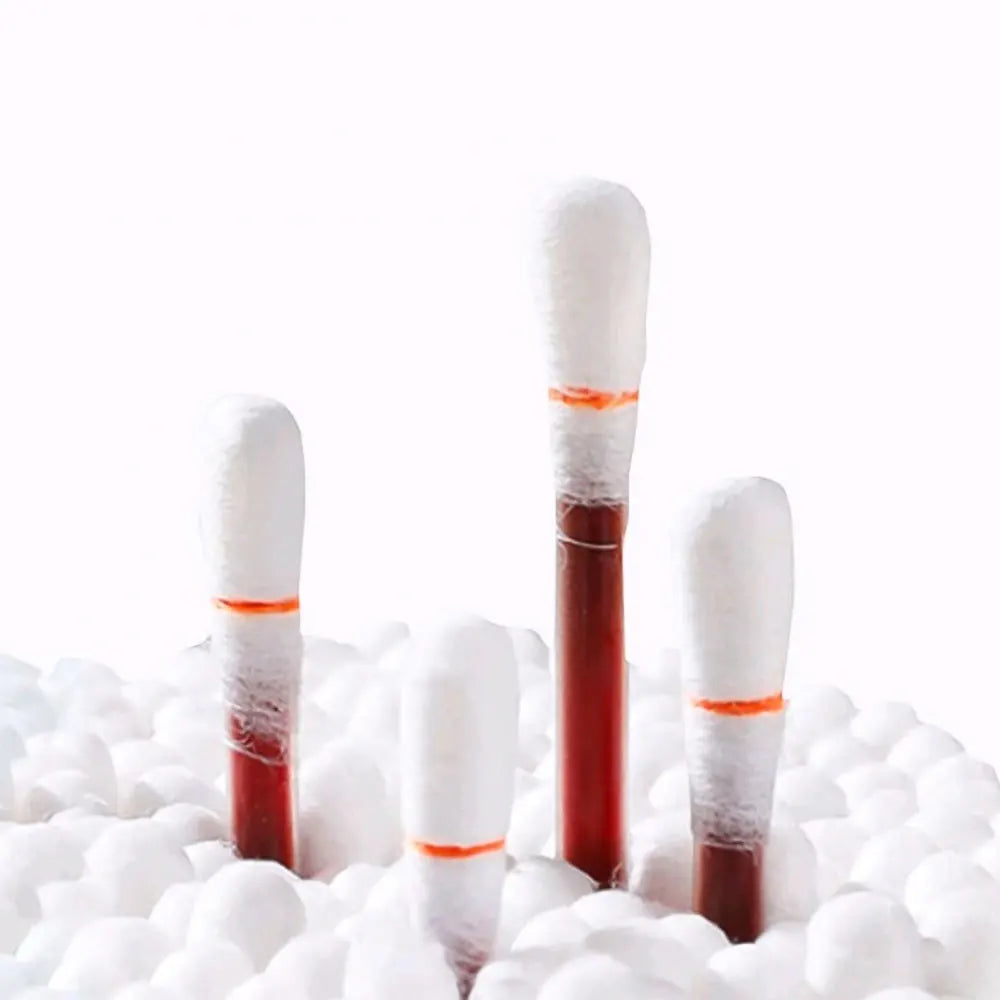 Three disposable medical iodine cotton swabs standing upright on a bed of white cotton balls.
