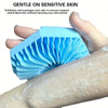 A hand holds a blue silicone exfoliating shower scrub brush against a person's arm.