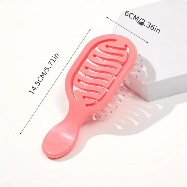 A pink mini travel hair brush with silicone bristles is shown next to its packaging.