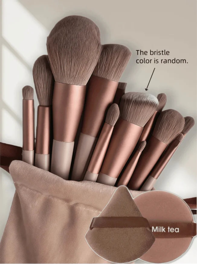 A collection of 15 makeup brushes in various shades of rose gold and nude tones displayed in a fabric holder.